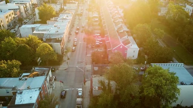 Tracking aerial shot of a neighborhood in Philadelphia at sunrise, with a natural lens flare from the morning sun.