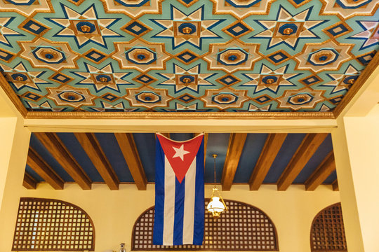 Cuban flag hangs in a building with a colorful ceiling
