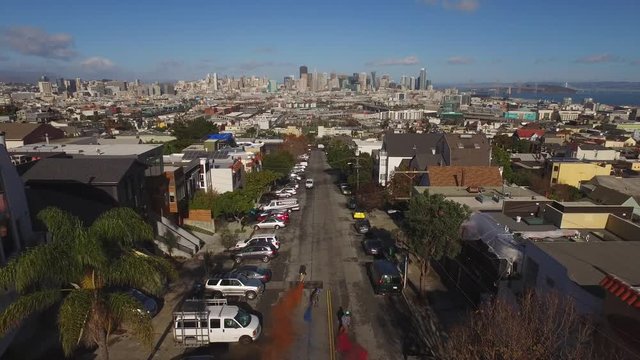 Smoke bomb skateboarders at high speed fly down California roads with beautiful cityscape in background. Shot with a drone.