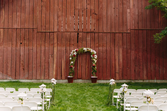 Wedding Arbor in front of Rustic Red Barn with Seating for Ceremony