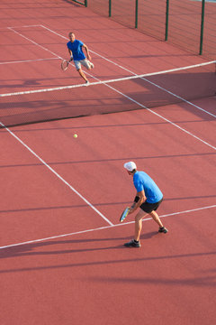 Men playing tennis on slag court