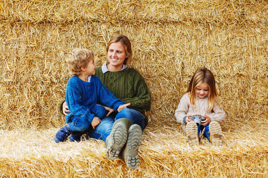 Mother and kids having fun sitting on a haystack.