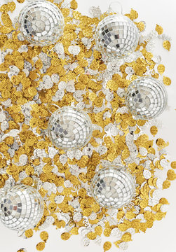 Mirrored disco balls on gold and silver party confetti.