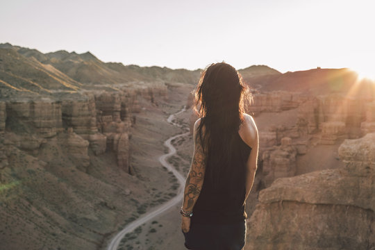 portrait of tattoed beautiufl woman enjoying sunset above charyn canyon