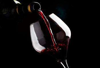 Red wine from grapes of pinot noir varieties poured into large wine glass, wine tasting, on dark background, low key, selective focus - obrazy, fototapety, plakaty