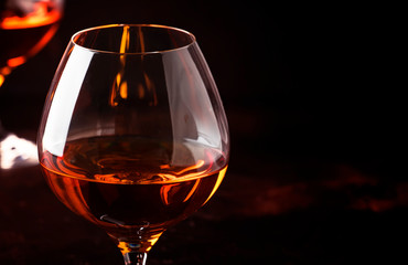 Grape brandy in shot glass, dark brown background, selective focus