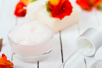 beauty product samples with roses on white wooden, soft light