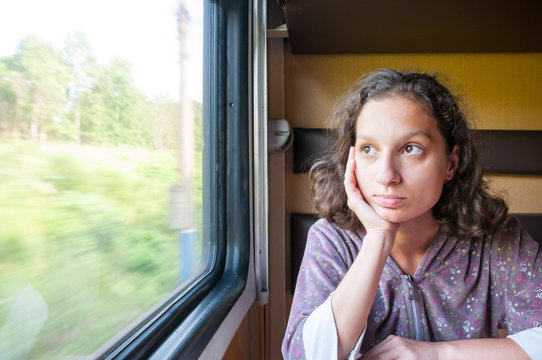 Teen girl sitting in compartment car of train in summer, traveling