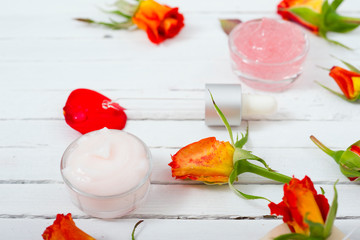 beauty product samples with roses on white wooden, soft light