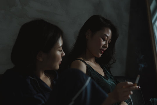 Two young Chinese girls smoking and chatting