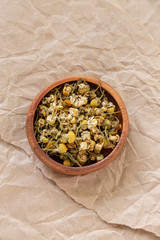 Dried chamomille flowers in a wood bowl.