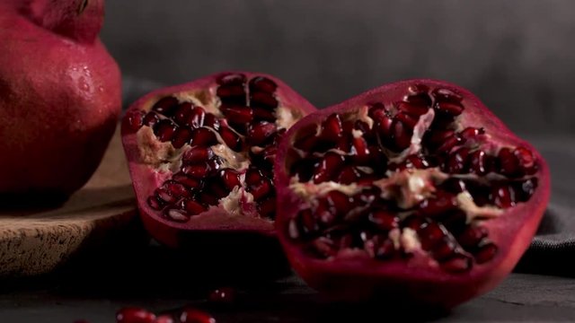 Ripe pomegranate fruit and pomegranate seeds on dark background, close-up. Healthy vegetarian antioxidant organic diet food