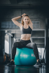 Young attractive woman fitness doing exercises workout on ball in gym. Woman stretching the muscles and relaxing after exercise at fitness gym club.