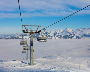 An overhead cable car, summits of the Alps rising from sea of fog - a wintertime view from the Fronalpstock mountain in the Swiss canton of Schwyz