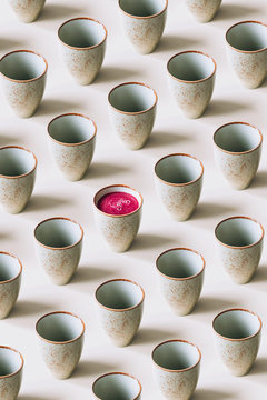 Pattern of empty mugs with just one mug with beetroot juice
