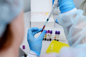 Dna test in the lab. A lab technician dripping blood into a test tube from a dispenser.