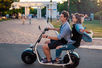 Fototapeta na wymiar Lovely young couple driving electric bike during summer. Modern city dating and transportation