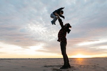 Man lifting son up on shoreline