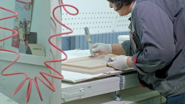 a woman, a worker, spat the door surface. production of interior doors of wood