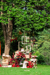 An outdoor wedding, a dessert area under a tree, with cakes and desserts on the dessert table.green gass