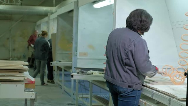 a woman, a worker, spat the door surface. production of interior doors of wood
