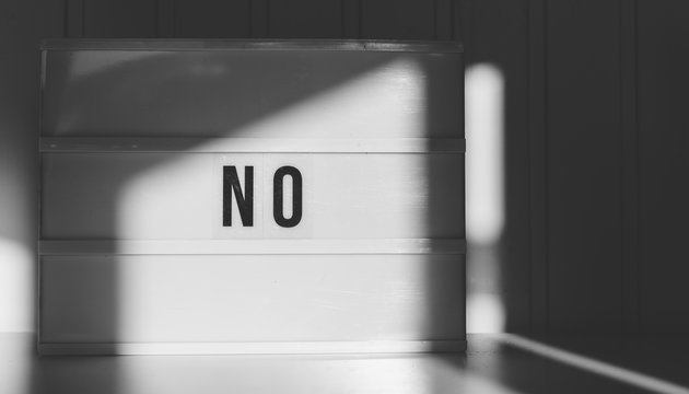 Black and white image of the word No spelled out on a light box.