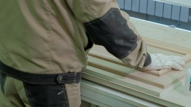 male worker gluing wooden blanks for a door. production of interior doors of wood