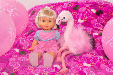 Children's toys, baby doll and pink flamingo, gifts for children. Holiday with balloons.