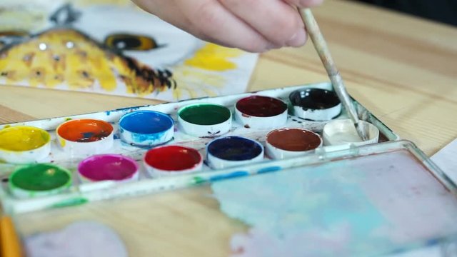 The artist dips a brush in watercolor