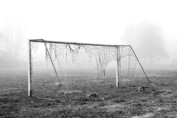 Broken soccer goal on a foggy field.