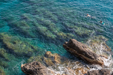 Swimming in the crystal clear water and rocks at Monterosso al Mare on the Ligurian coast in Italy