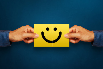 Hand of client show a feedback with smiley face card. Service rating, satisfaction concept