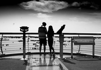 silhouette of lovers sitting on pier at sunset