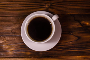 Cup of dark coffee on wooden table. Top view