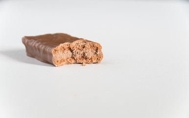 Chocolate biscuit with a bite taken on a white