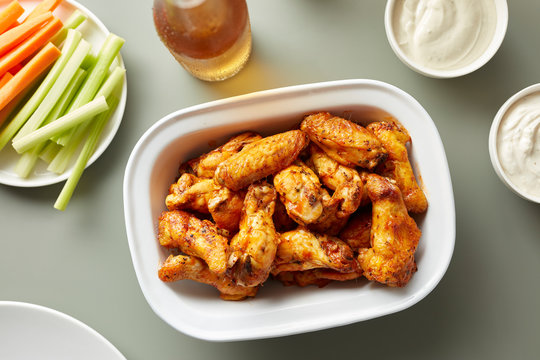 Delicious chicken wings in bowl with beer and vegetables.