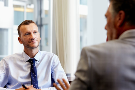 Businessman Listening To Colleague In Office