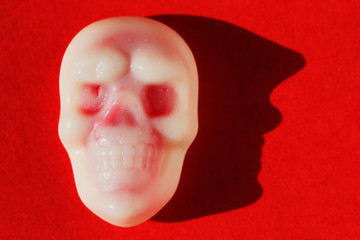 Closeup of white and red Halloween-themed skull candy on a red background