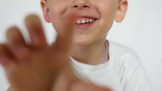 A joyful child smiles and pulls his hand forward to the camera.