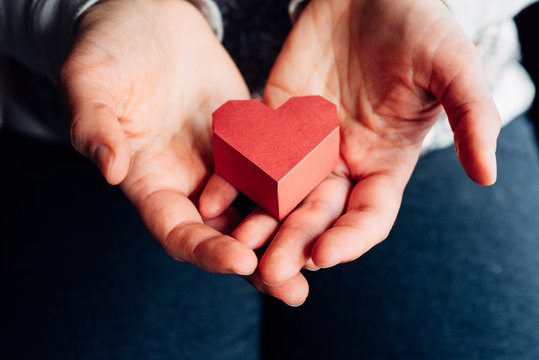 Woman's hands holding a red paper heart