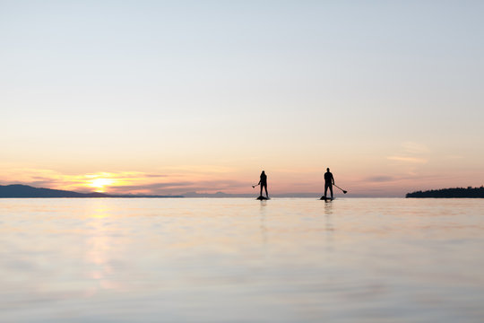 Couple stand up paddle boarding together at sunrise