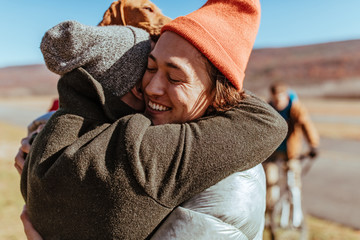 Friends hugging on an airfield after flying glider planes