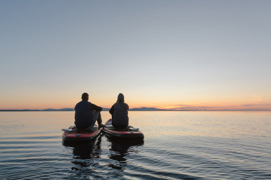 Couple stand up paddle boarding together at sunrise