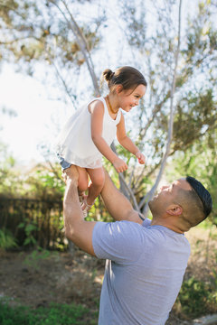 Two dads throwing young kid in the air
