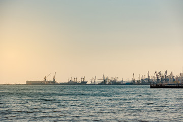 Silhouette of port cranes and ships at sunset in evening light