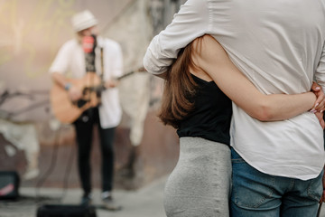 Fototapeta na wymiar Couple in love listening street musician playing guitar
