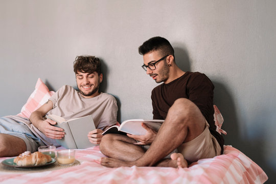 Men reading books on bed