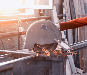 Production of pvc windows, worker cuts a metal profile on a circular saw, close-up, hand, sun