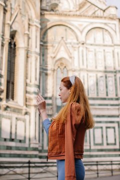 Side view portrait of redhead girl taking picture of Duomo in Florence