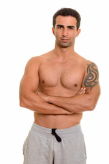 Fototapeta premium Portrait of young handsome Persian man shirtless with arms crossed
